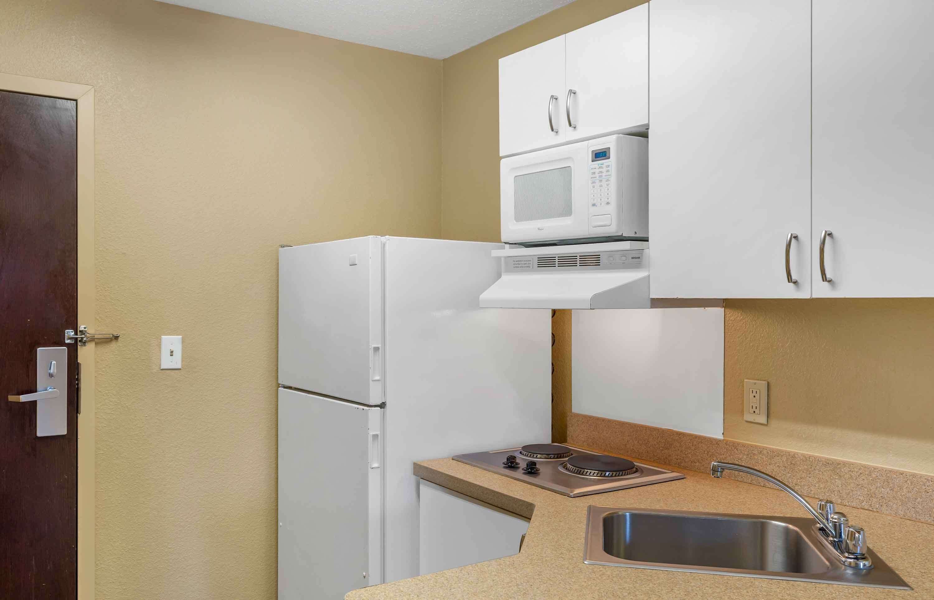 Una kitchenette pequeña con un refrigerador blanco, microondas, estufa y lavamanos.