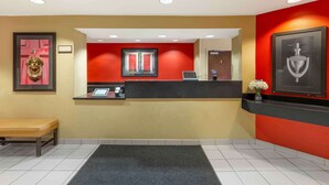 A reception area with a counter, a bench, a door with a number, and a framed picture on the wall. - Extended Stay America Suites Providence Warwick (Warwick)