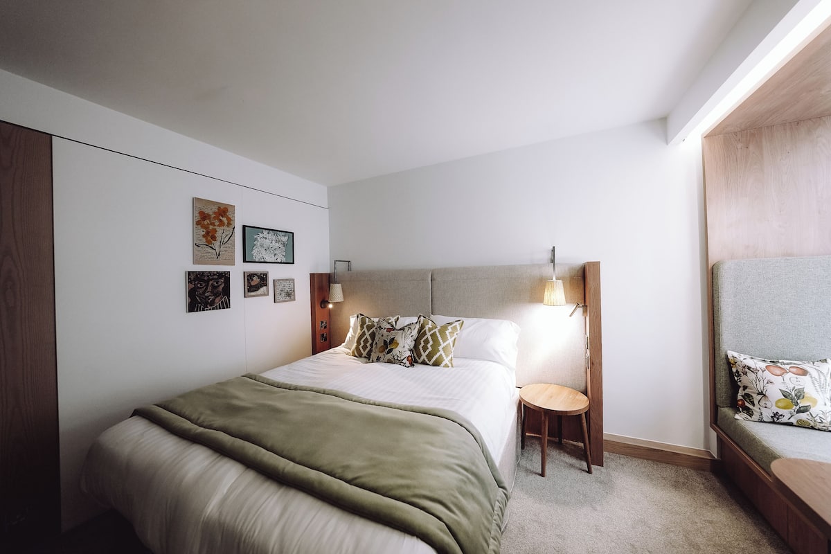 Camera da letto moderna con un letto, comodini e opere d'arte alle pareti.