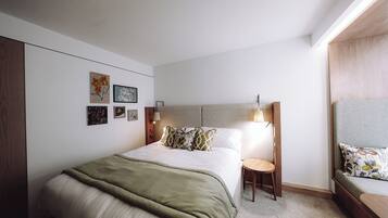 A modern bedroom with a bed, bedside tables, and wall art.