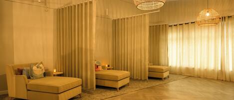 A spacious room with a large bed, two armchairs, and a small table.