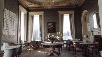A dining room with a chandelier, patterned wallpaper, and a table with chairs.