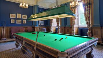 A pool table with balls, a chandelier, and framed pictures on the wall.