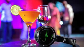 A martini glass with a lime wedge, a wine glass, and a pair of headphones on a table.