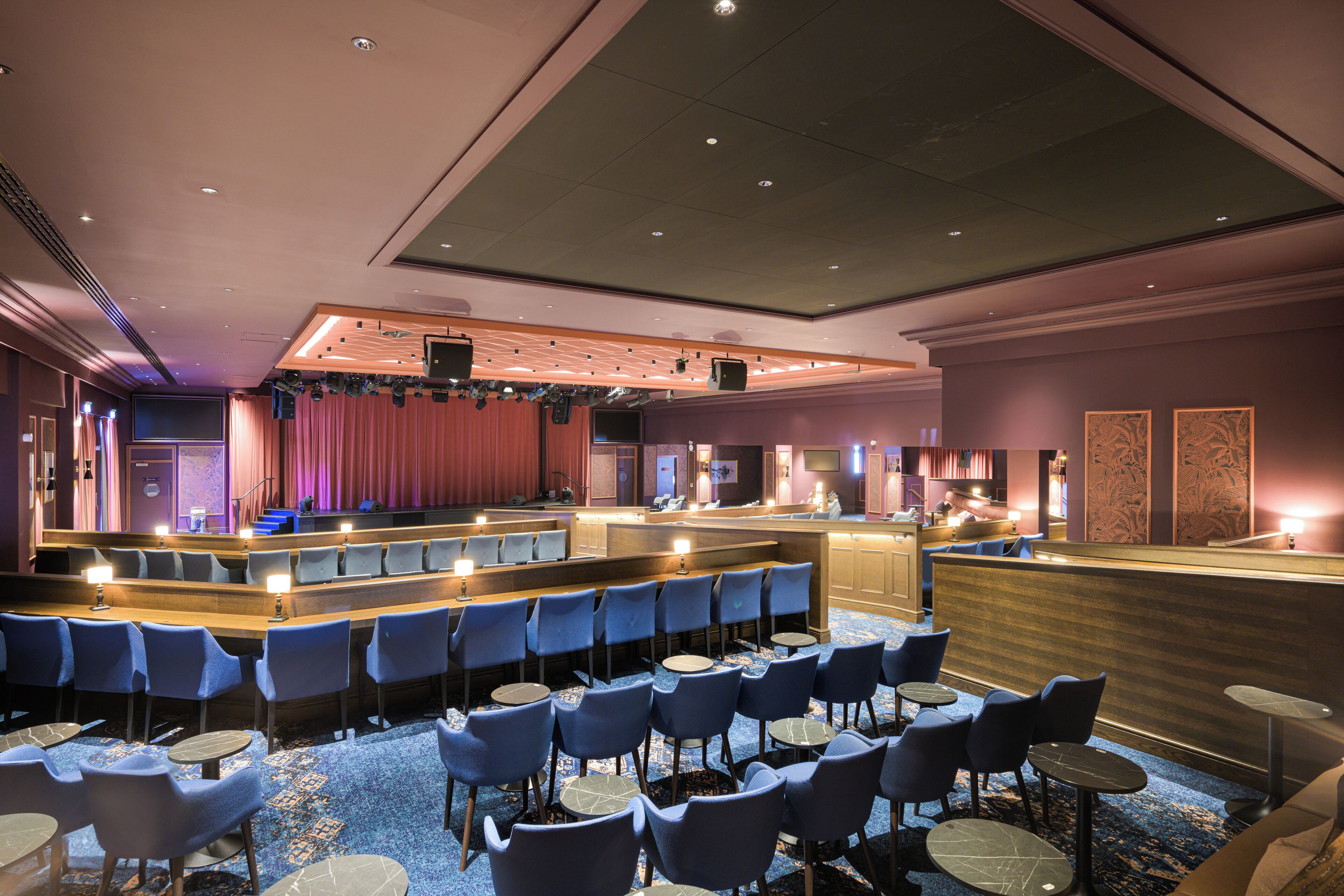 A hotel lobby with a stage, seating area, and bar.