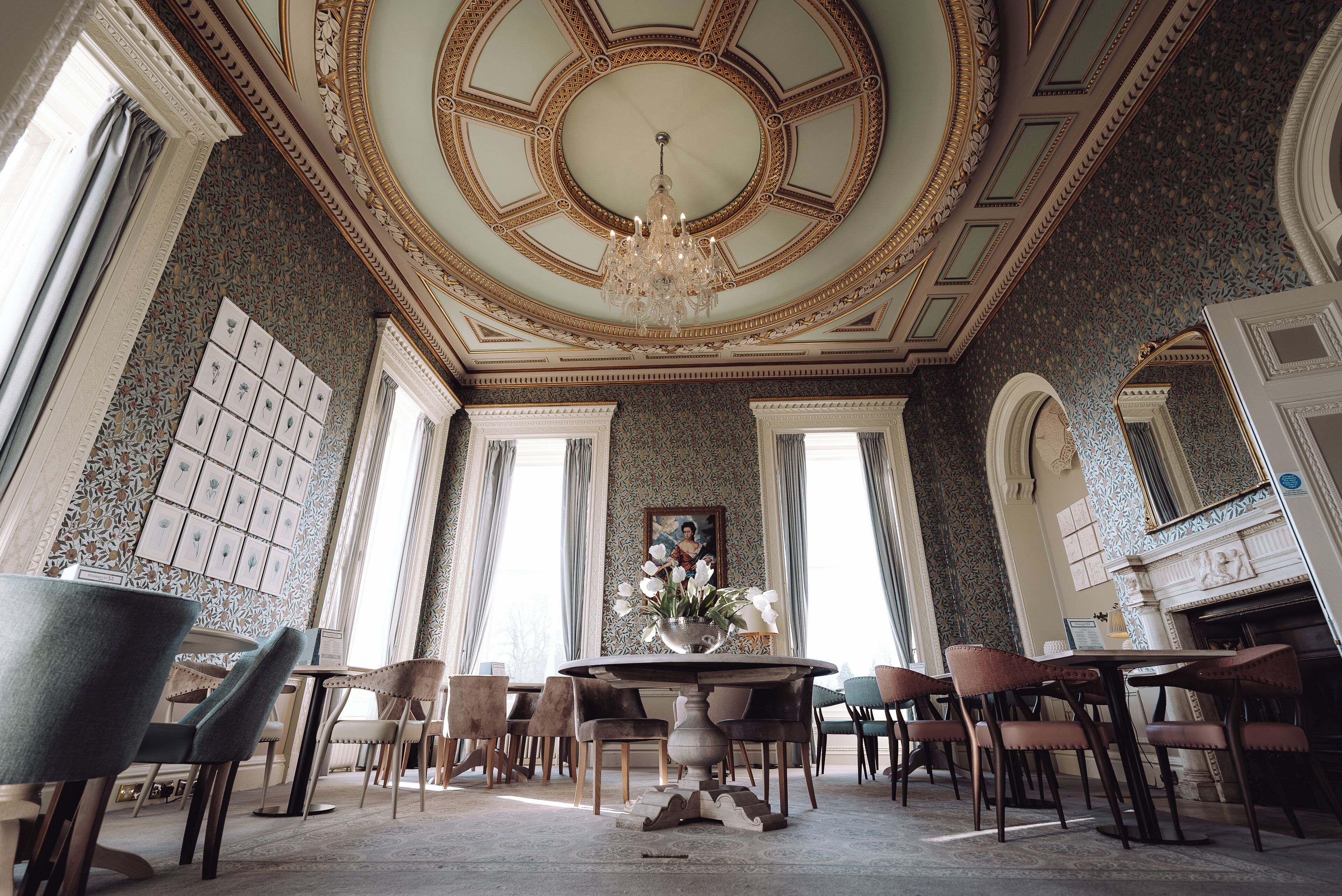 A grand room with a large chandelier, ornate ceiling, and a fireplace.
