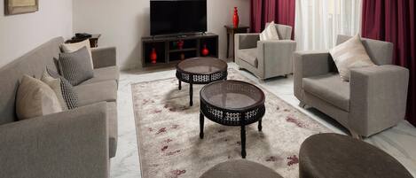 A living room with a sofa, armchairs, a TV, and decorative items.