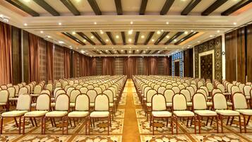 Une salle de conférence avec des rangées de chaises, une moquette à motifs et un plafond doté d’un éclairage encastré.