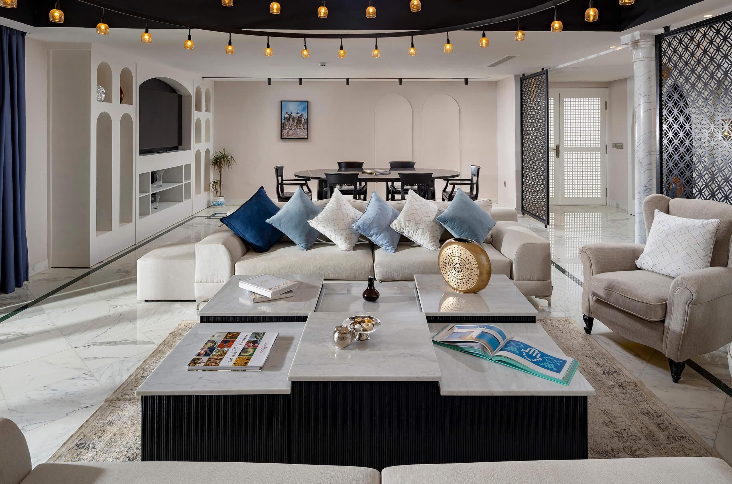 A modern living room with a sofa, coffee table, and a dining area with chairs and a table.