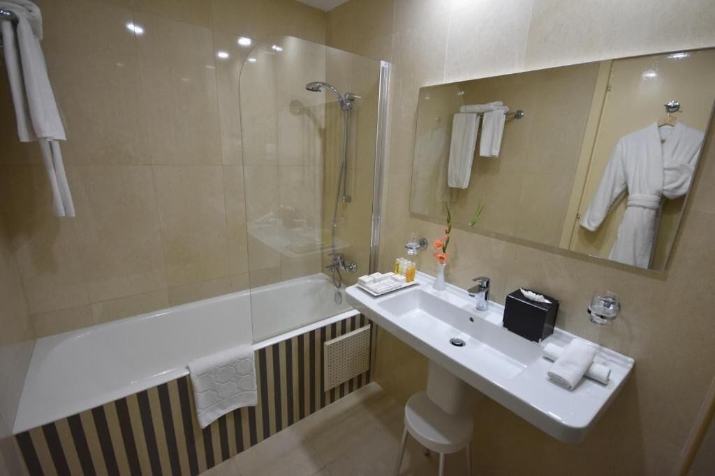 Een moderne badkamer met een bad, wastafel, spiegel en douche.
