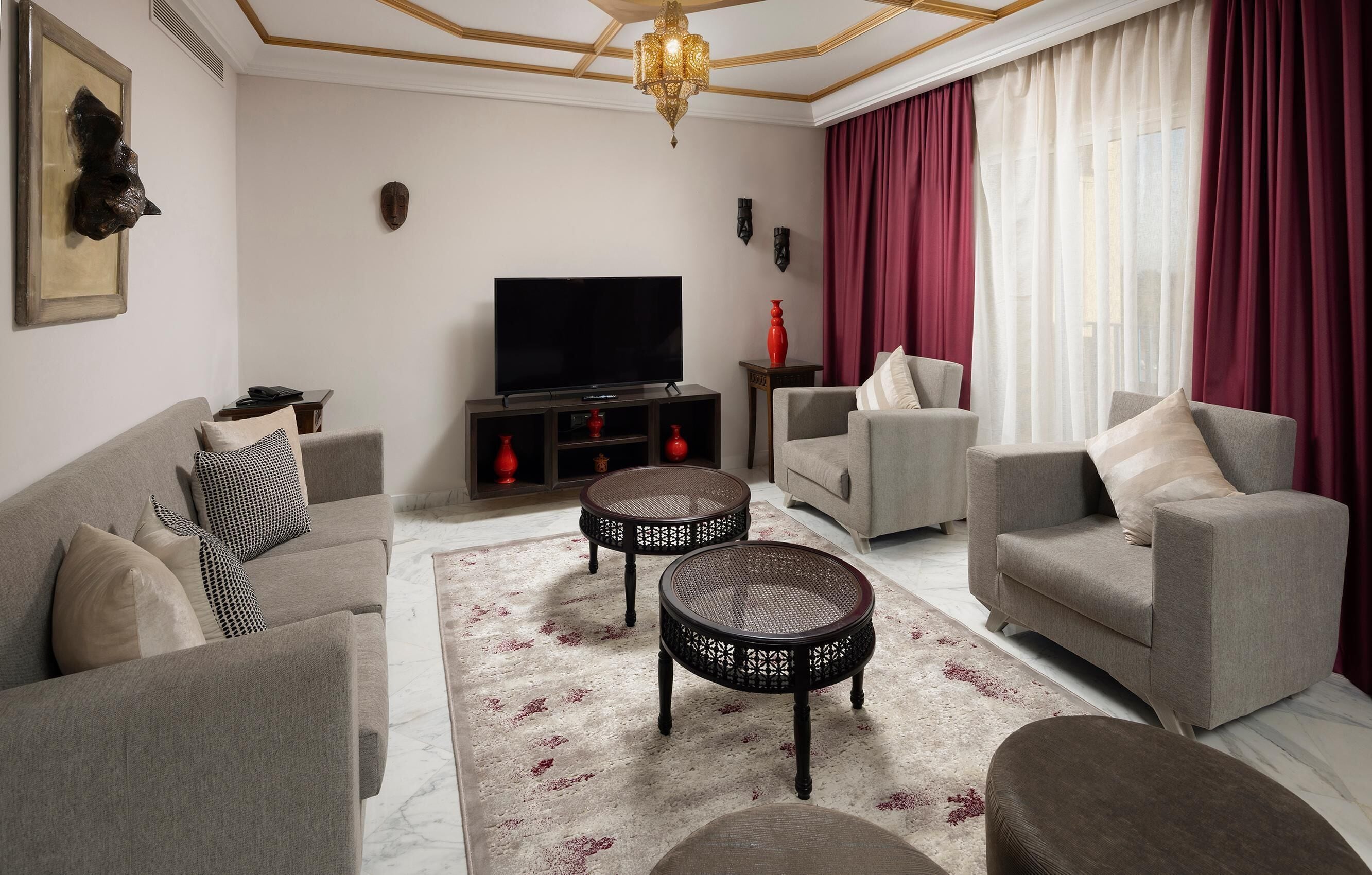 A living room with a sofa, armchairs, a TV, and decorative items.