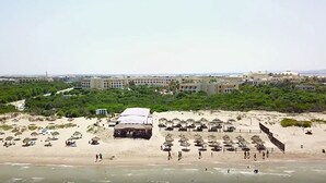 Een strand met parasols en een groot gebouw op de achtergrond.