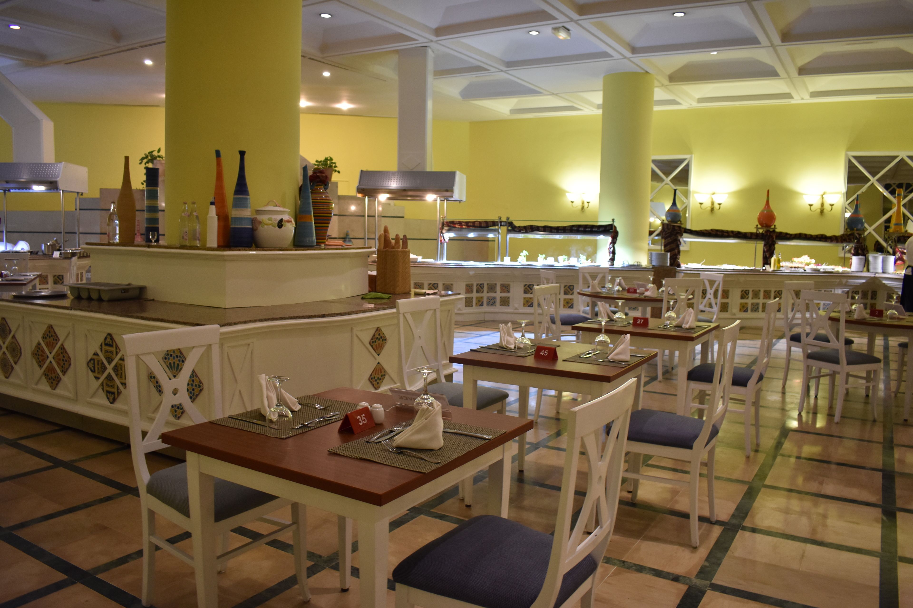 Un restaurant dont le mobilier est blanc, les murs jaunes et le sol carrelé.