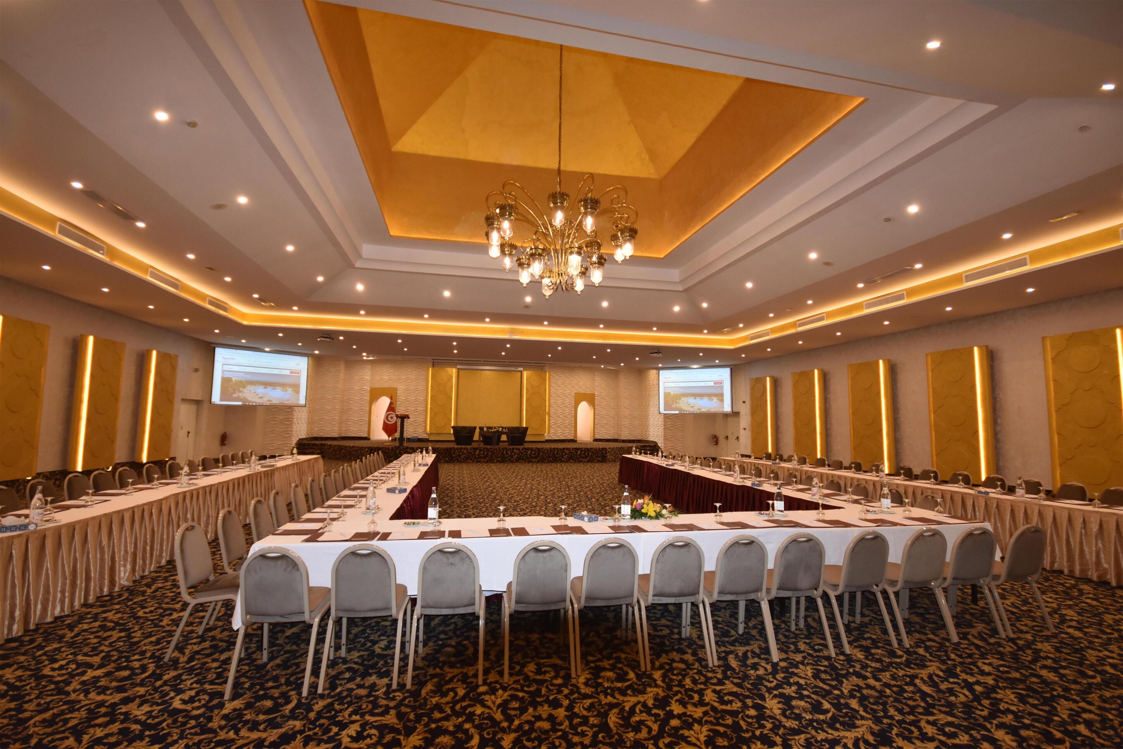 A conference room with a long table, chairs, a podium, and a projector screen.