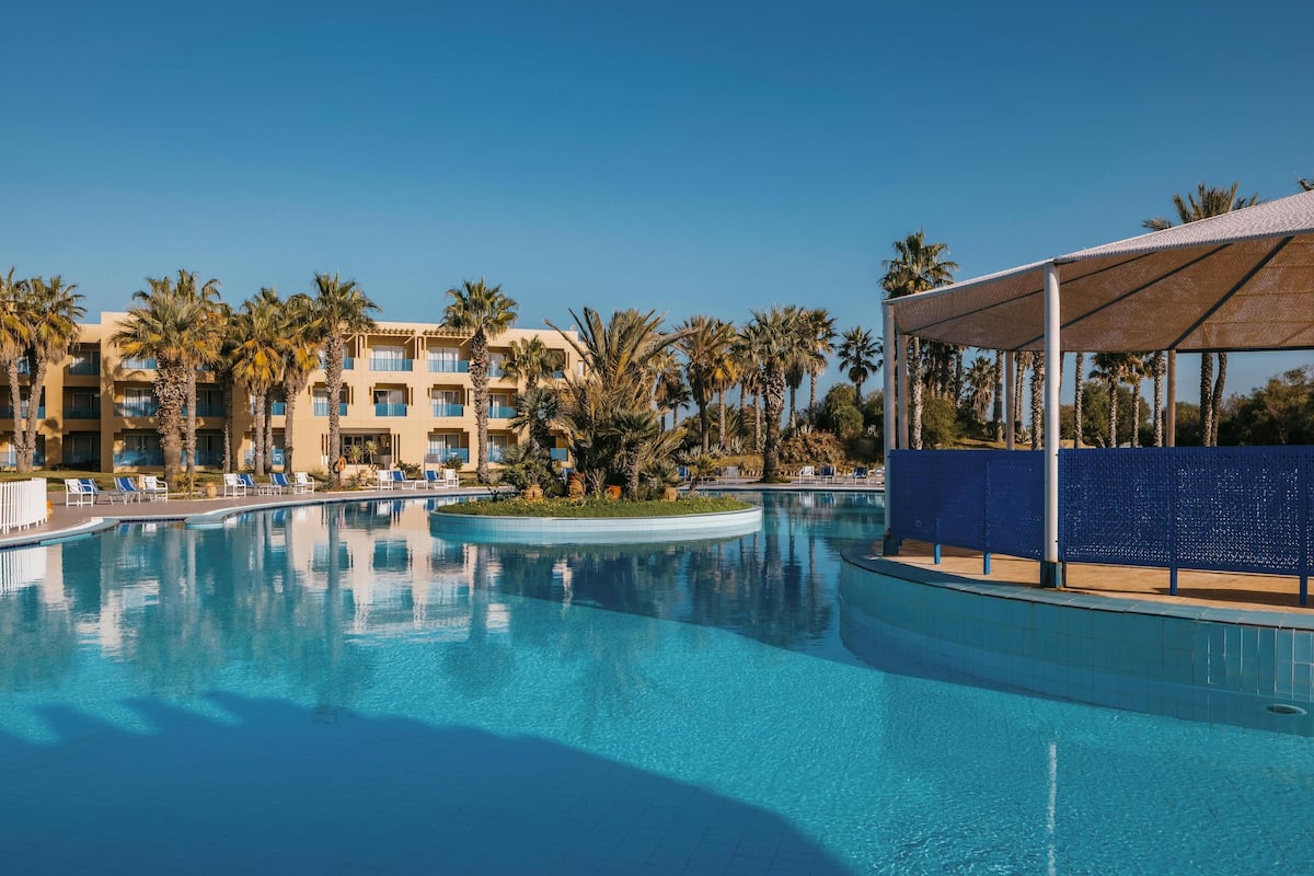Un área de piscina con sillones reclinables y un edificio con varios balcones.