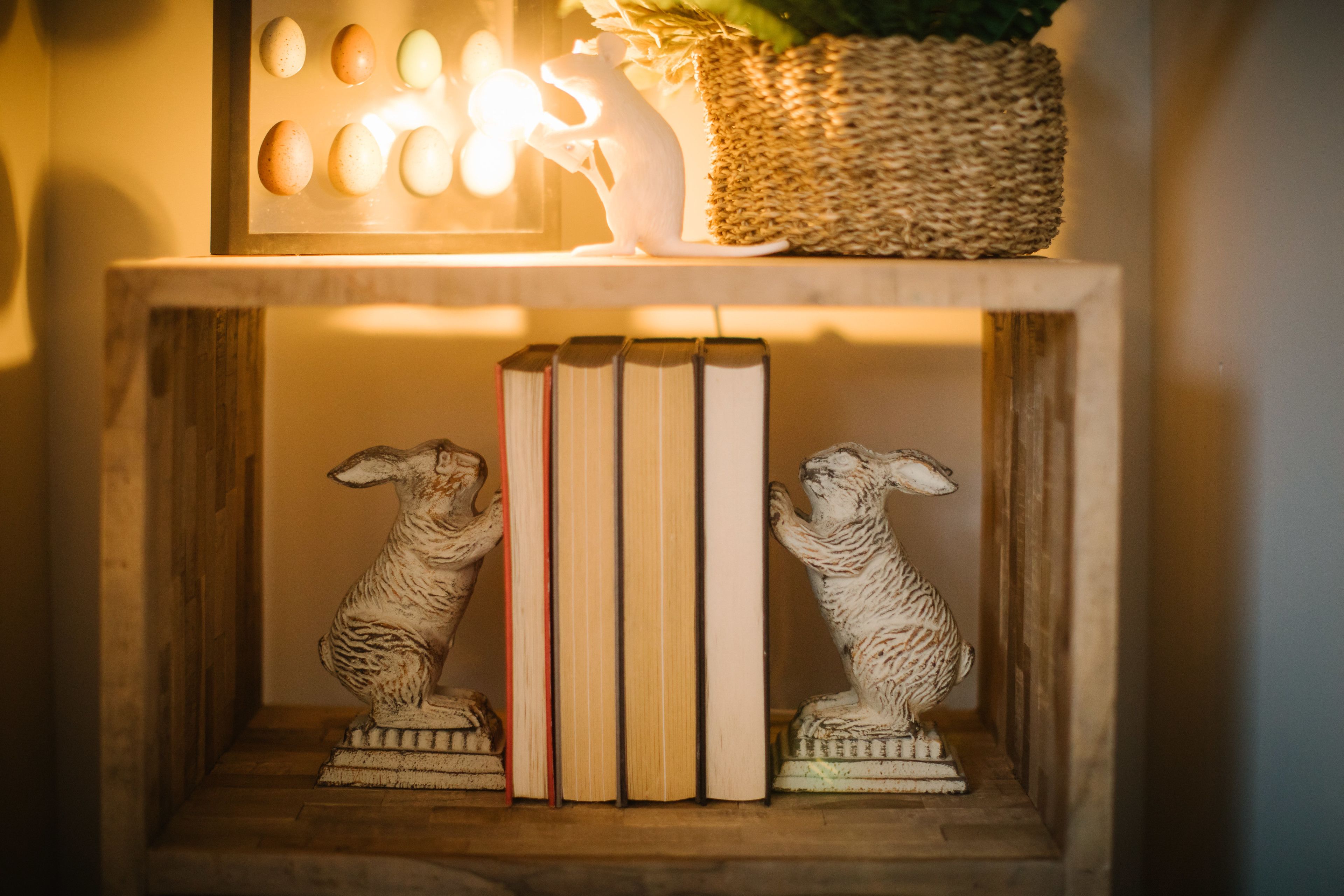 Een houten plank met twee dierenbeeldjes, een mand en een rij boeken.