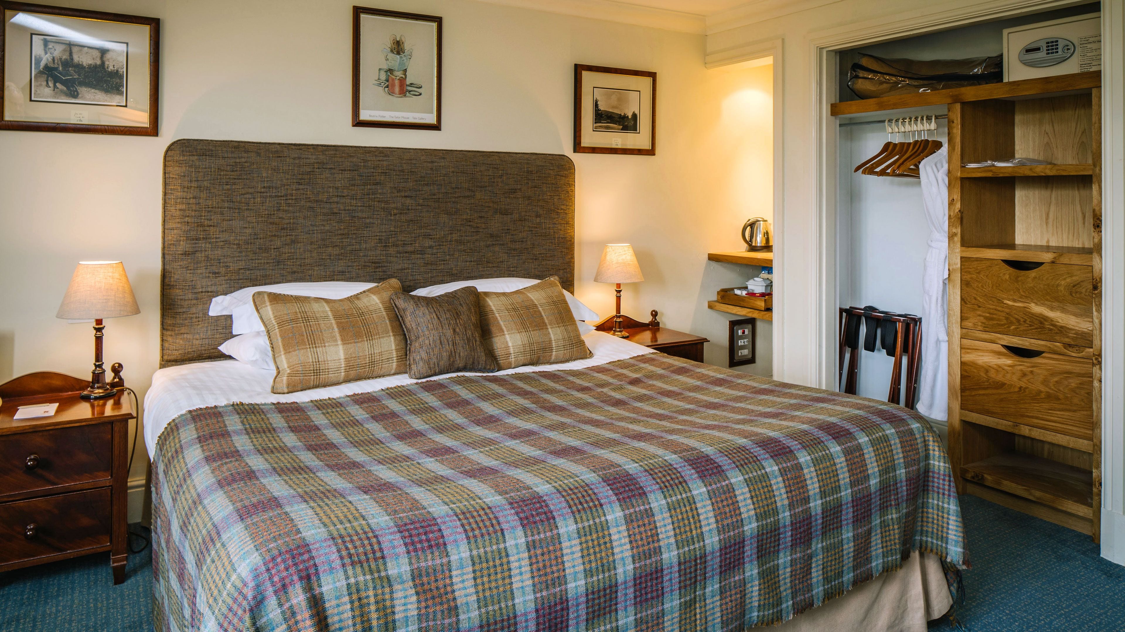 A neatly made bed with a plaid bedspread, two bedside lamps, and a wooden headboard.