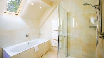 A modern bathroom with a glass-enclosed shower, a freestanding bathtub, and a skylight.