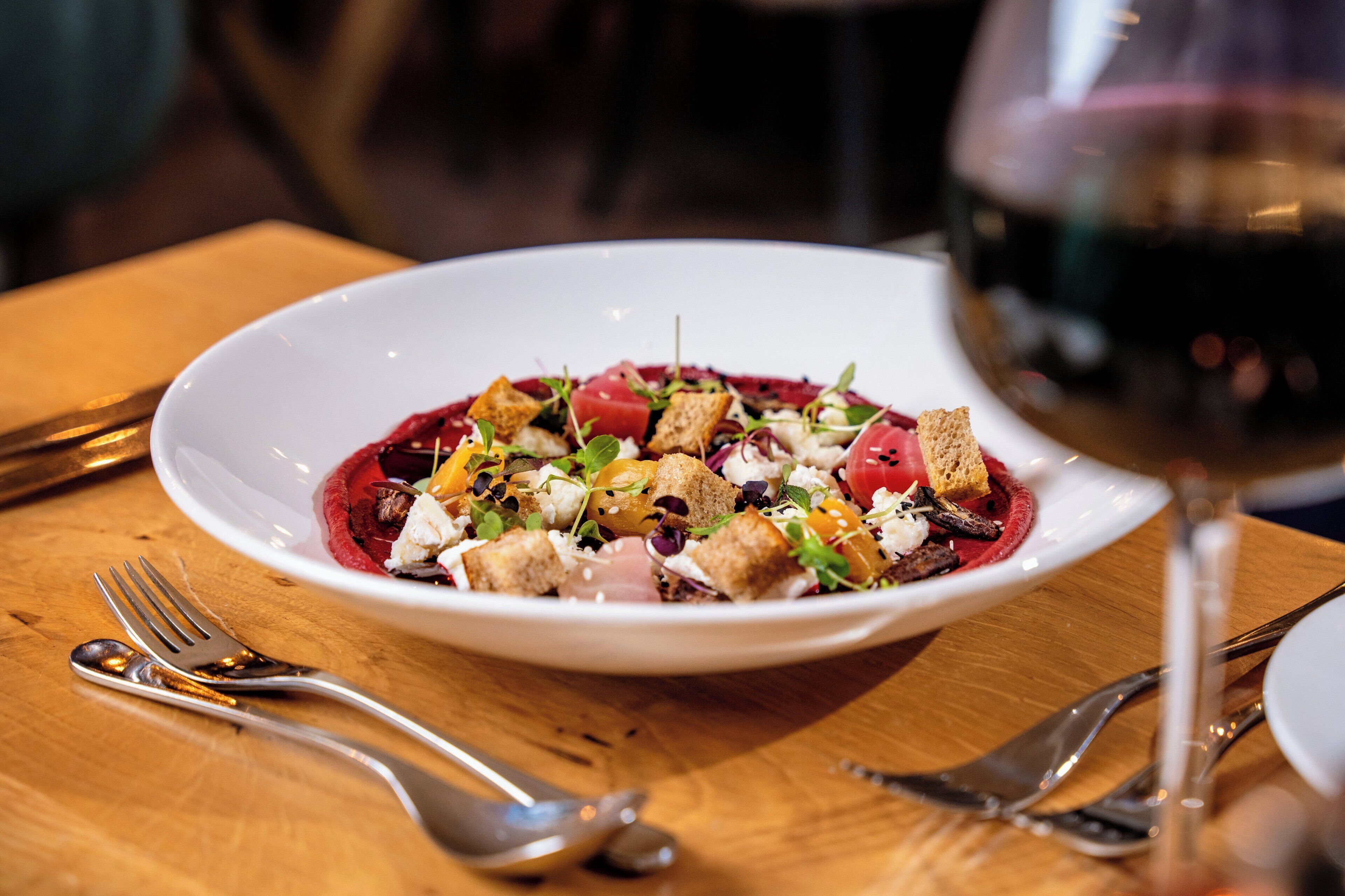 A white plate with a salad on a wooden table.