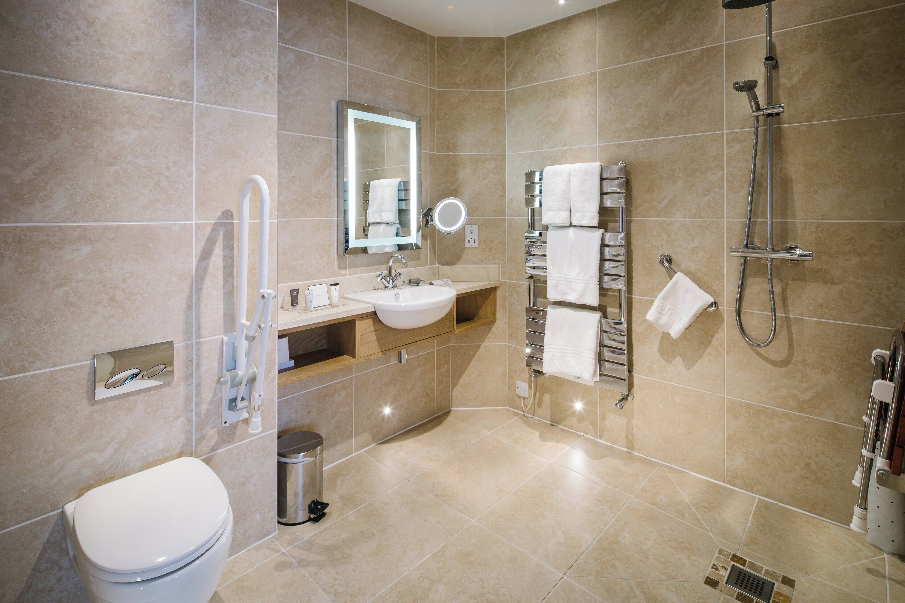 A modern bathroom with a toilet, sink, mirror, towel rack, and shower.