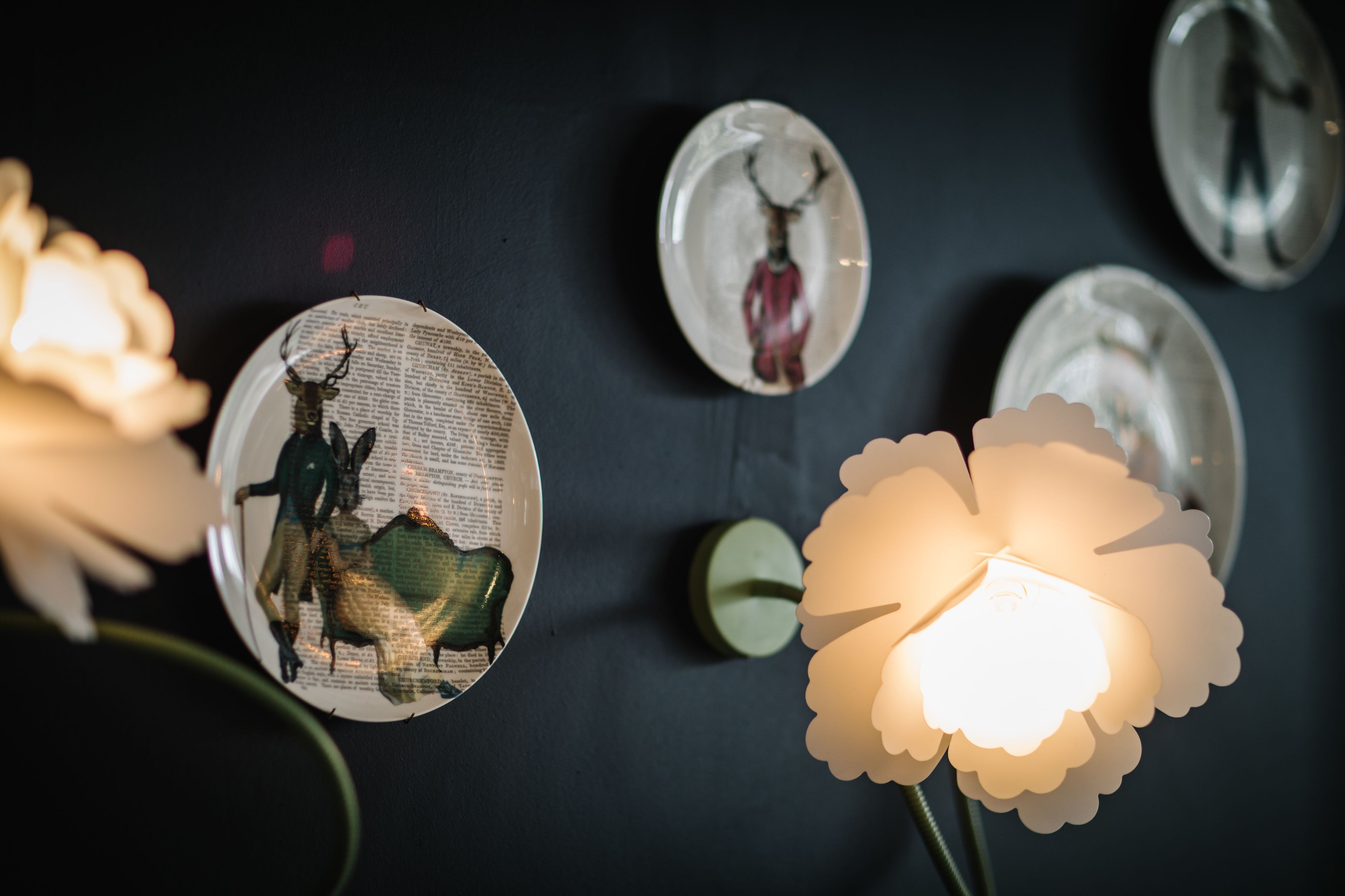 A wall with decorative plates and a flower-shaped light fixture.