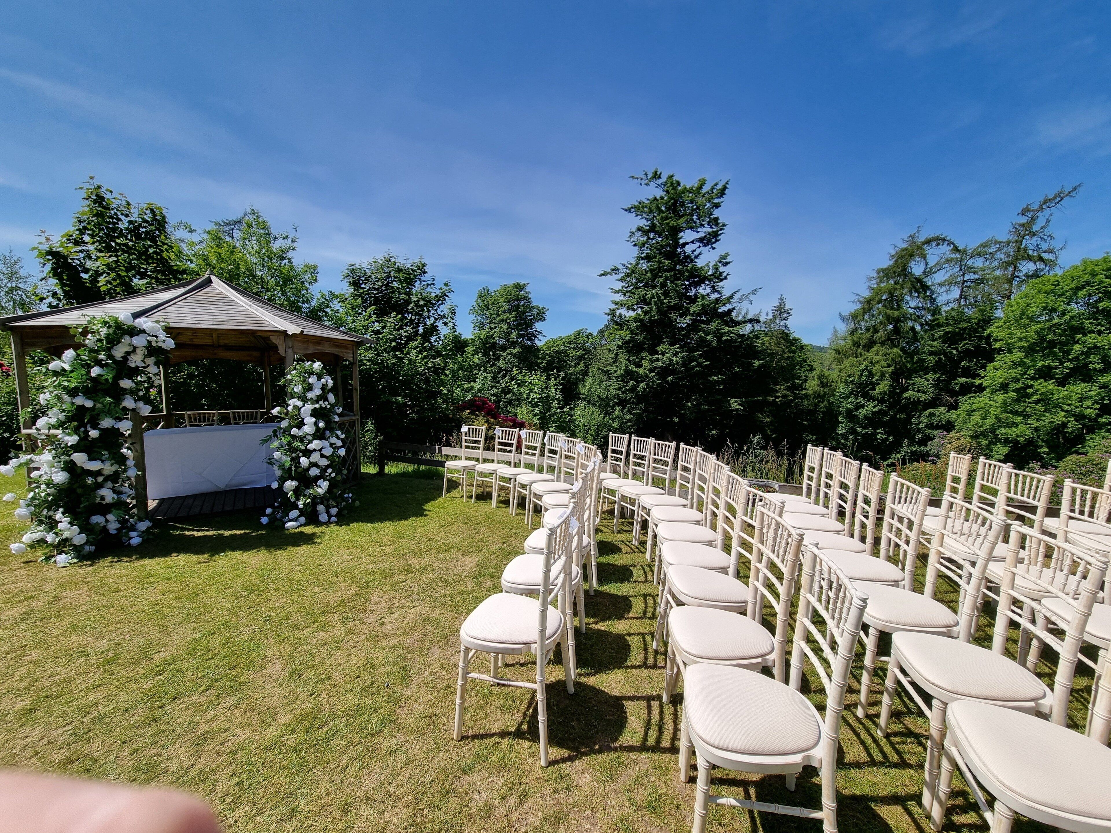 A gazebo with a white table and chairs arranged in a semi-circle.