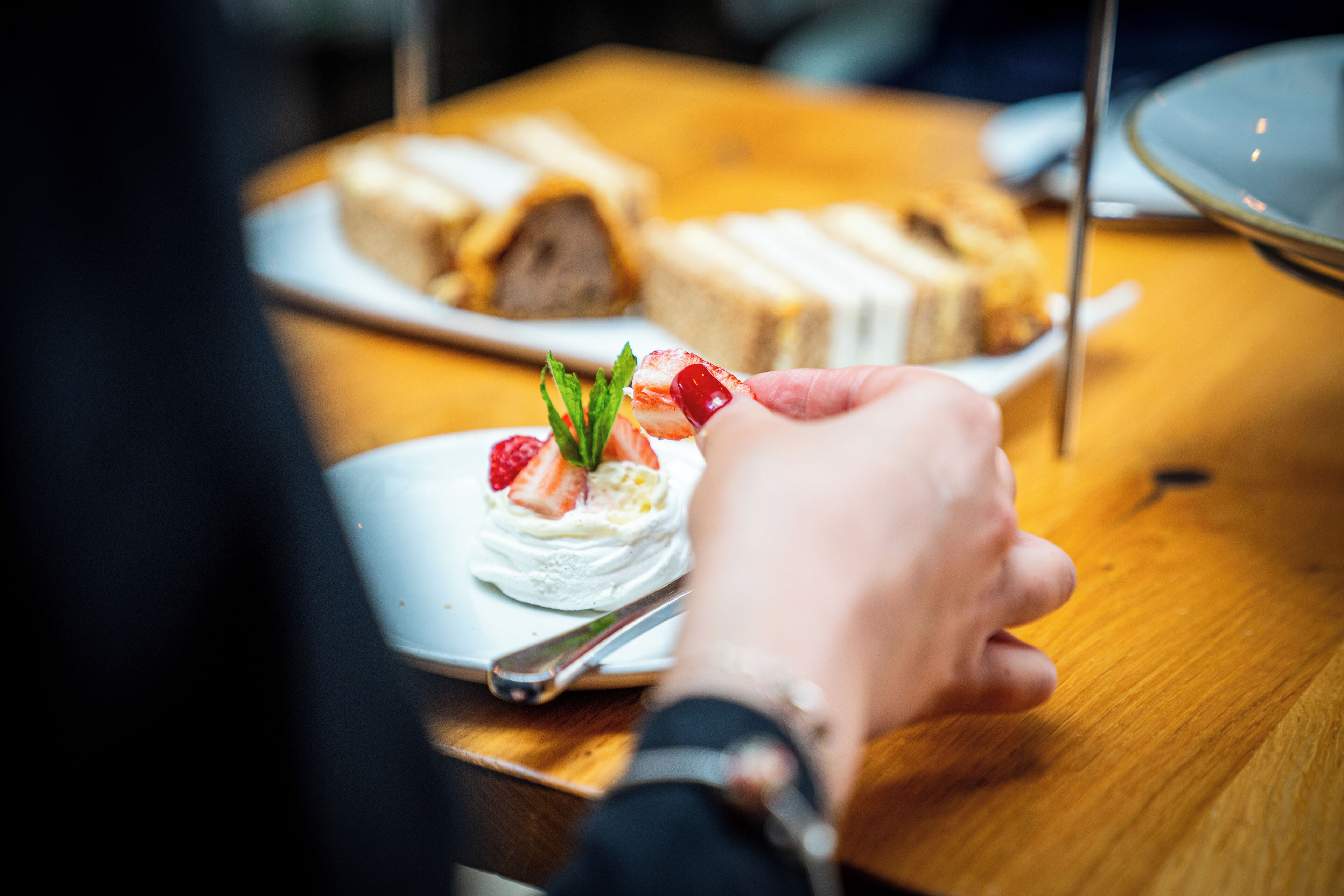 A person holding a dessert with strawberries and mint leaves.