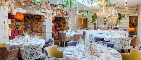 Un restaurant avec plusieurs tables rondes disposées pour accueillir les clients, entourées de chaises en osier.