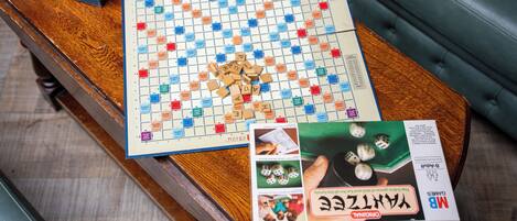 A Scrabble board game on a wooden table with dice and a box of Yatzee dice.