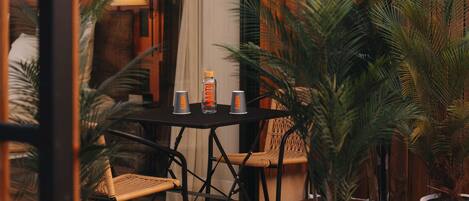 Una terraza de madera con una mesa, sillas, macetas y una lámpara.