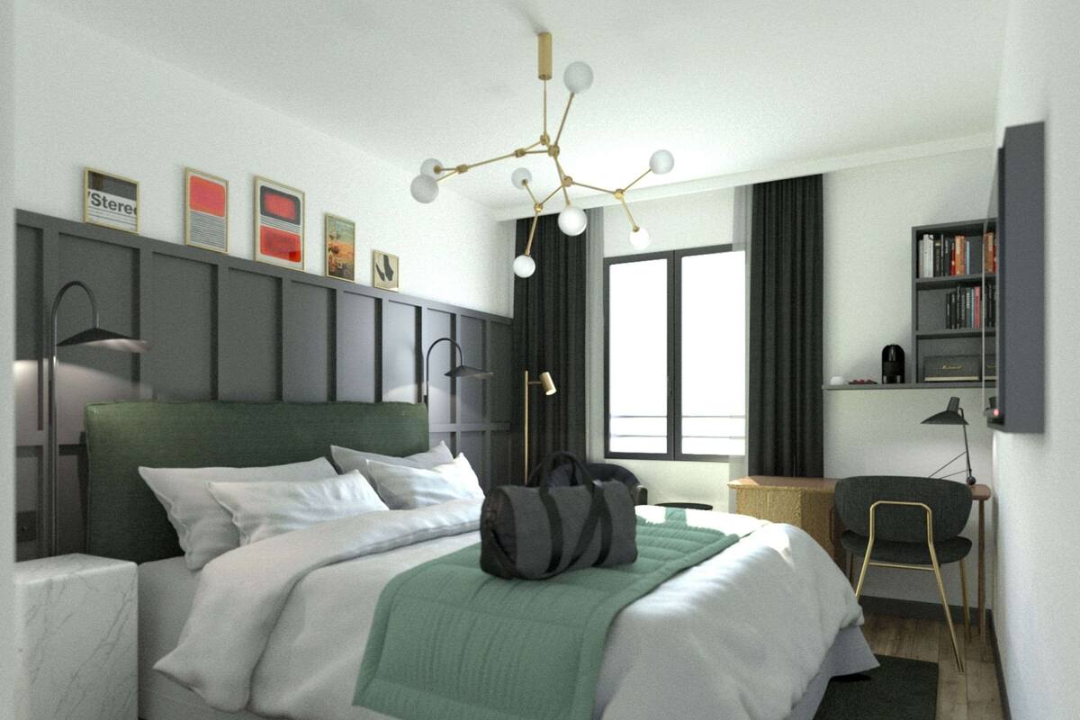 A modern hotel room with a bed, bedside table, lamp, bookshelf, and a desk with a chair.