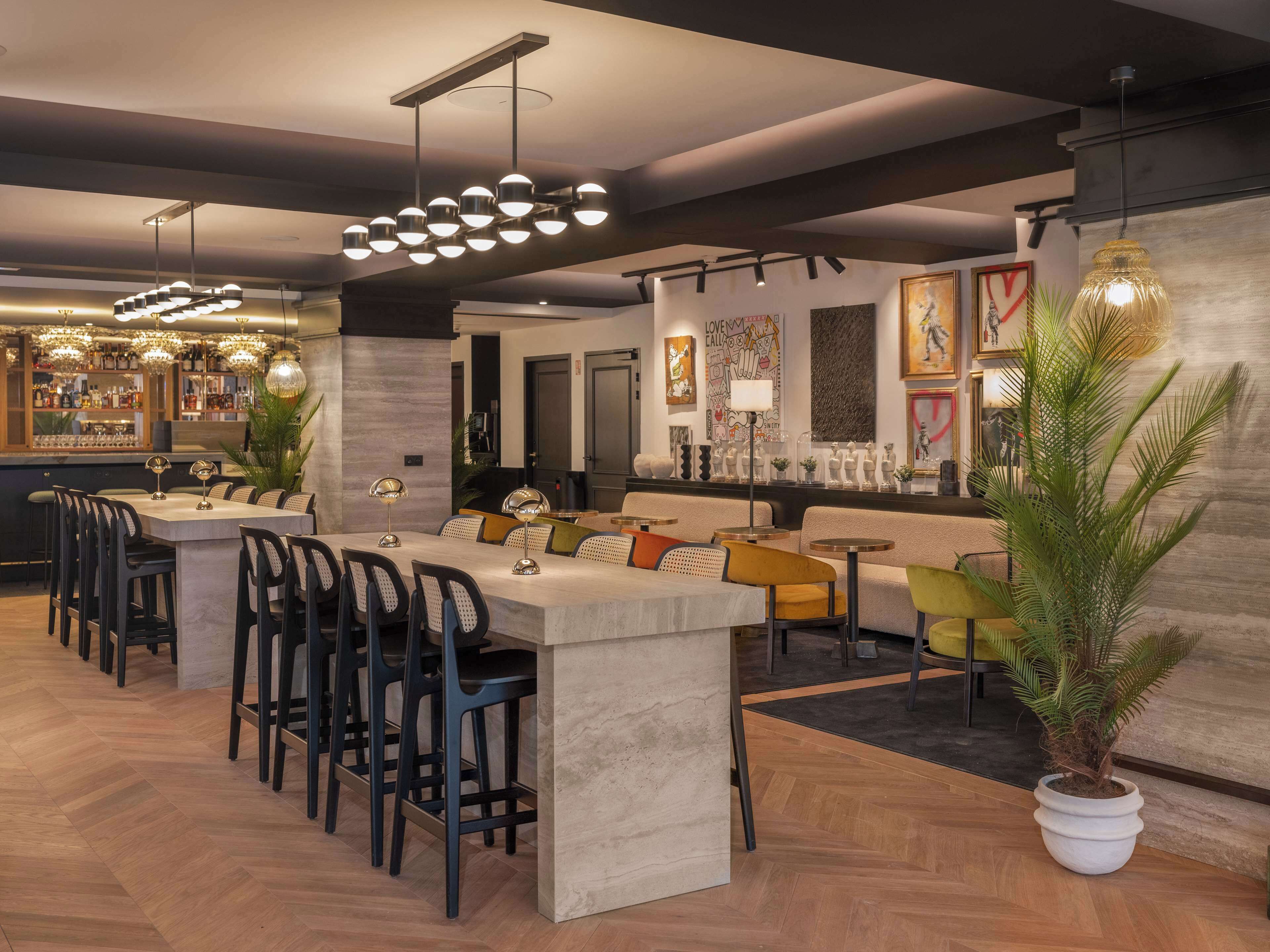 A modern dining area with a bar, multiple seating options, and a large potted plant.