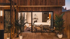 A wooden deck with a glass door leading to a bedroom with a bed, a chair, and a table. - Marty Hotel Bordeaux, Tapestry Collection by Hilton (Bordeaux)