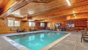 A pool area with wooden walls, a tiled floor, and a pool with a blue border. - Comfort Inn Denver West Arvada Station (Wheat Ridge)