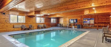 A pool area with wooden walls, a tiled floor, and a pool with a blue border.