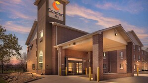 A Comfort Inn hotel with a brick facade, a prominent entrance, and a clear sky in the background.