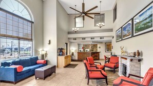 A spacious living area with a large window, a ceiling fan, a fireplace, and a bar area. - Comfort Inn Denver West Arvada Station (Wheat Ridge)