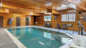 An indoor swimming pool with wooden walls, a lifeguard chair, and a sign indicating no diving.