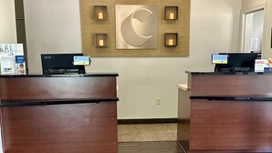 A reception area with two wooden reception desks, a wall-mounted crescent moon decoration, and a carpeted floor.
