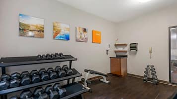A gym with dumbbells, a bench, and exercise equipment.