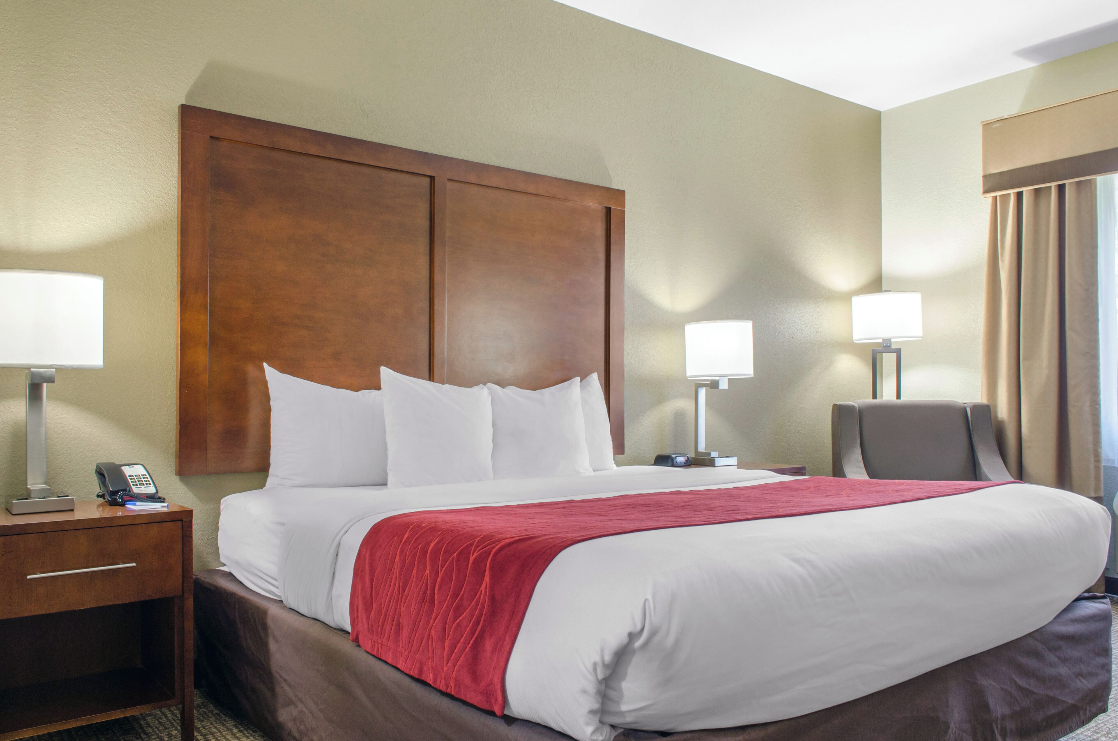 A hotel room with a large bed, two bedside tables, a desk, and a chair.