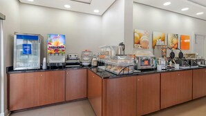 A breakfast bar with a juice dispenser, coffee maker, and various food containers. - Comfort Inn & Suites Covington - Mandeville (Covington)