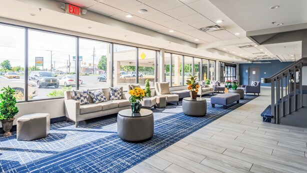 A spacious lobby with a blue patterned carpet, comfortable seating areas, and large windows offering a view of the street. - Quality Inn Roseville-Detroit North (Roseville)
