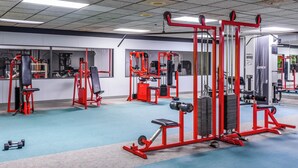 A gym with various exercise machines, mirrors, and a blue carpeted floor. - Quality Inn Roseville-Detroit North (Roseville)