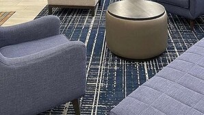 A modern lounge area with sofas, armchairs, and a flat-screen TV mounted on a stone wall. - Quality Inn Roseville-Detroit North (Roseville)