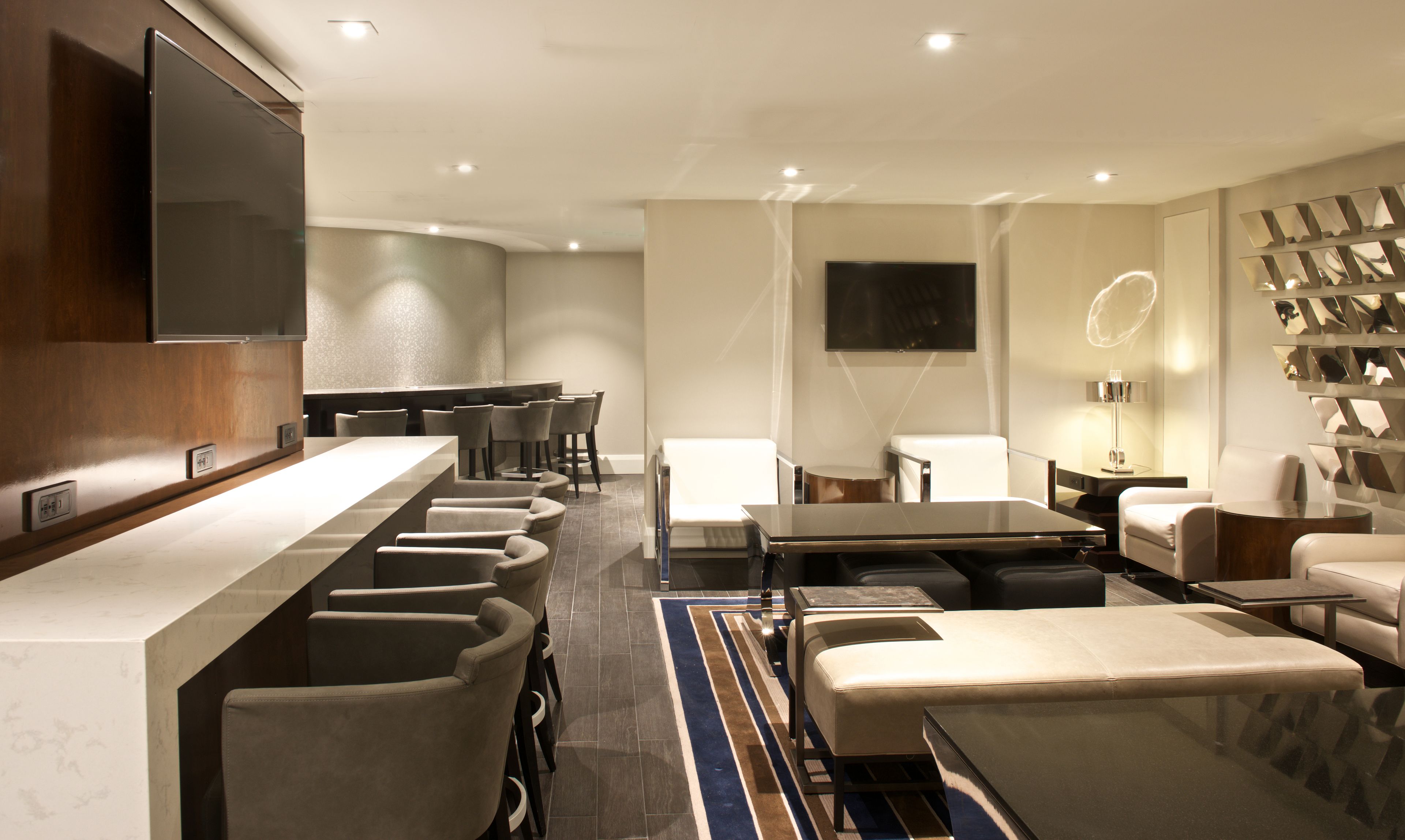 A modern hotel lobby with a bar area, seating, and a flat-screen TV.