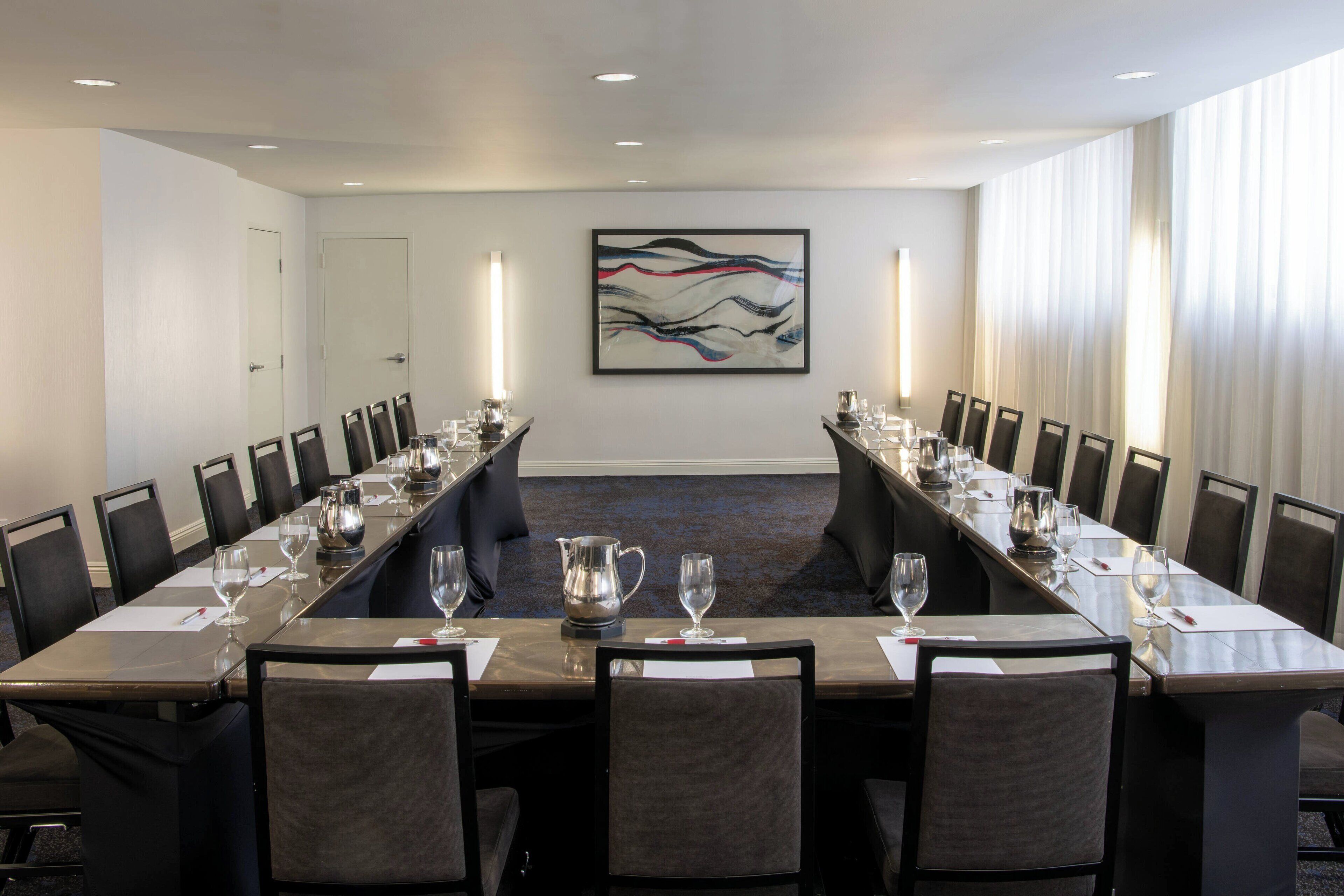 A conference room with a long table, chairs, and a large abstract painting on the wall.