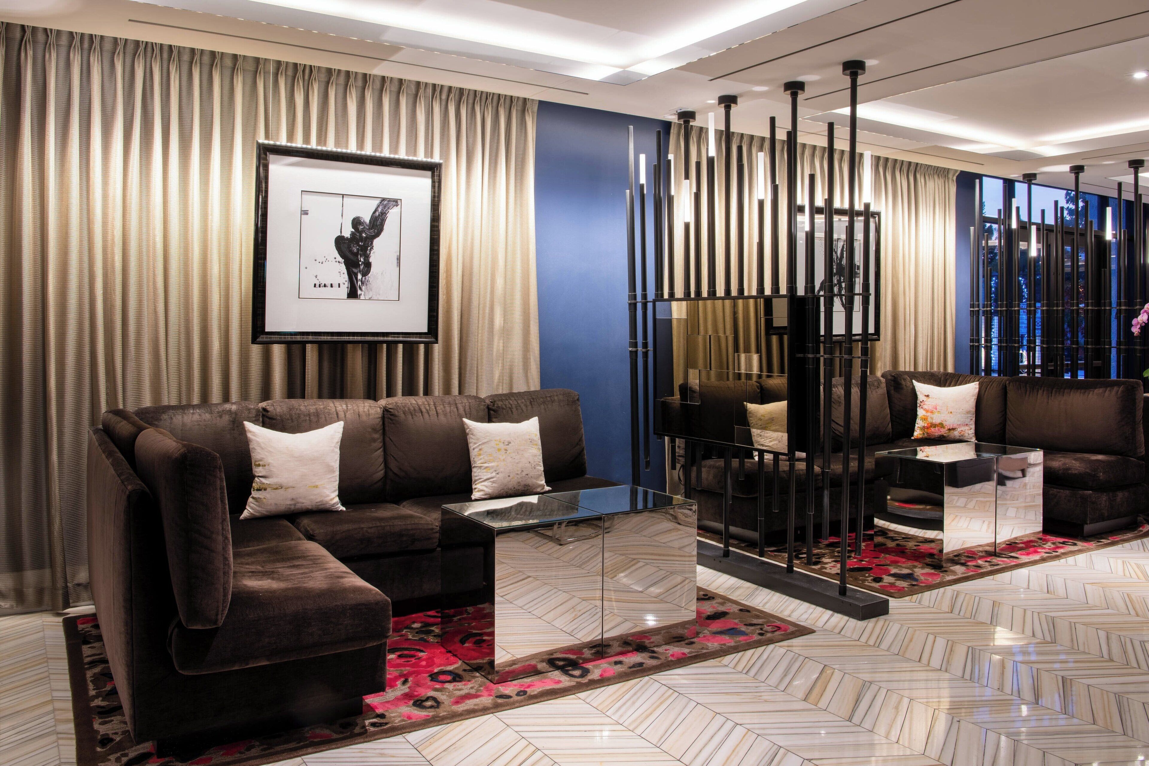 A modern living room with a sectional sofa, a glass coffee table, and a decorative wall panel.