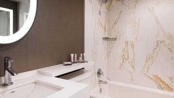 Un baño moderno con lavamanos doble, bañera y pared de ducha de mármol.