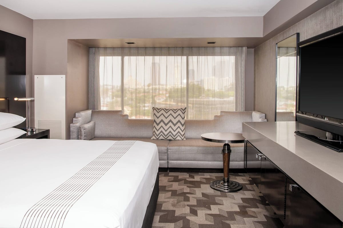 A hotel room with a large bed, a sofa, a small table, and a TV.